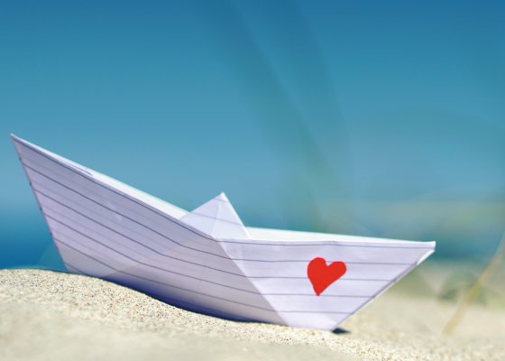 Papierboot mit Herz am Strand