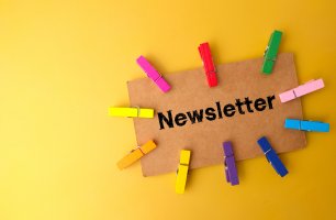 Colored wooden clips and brown card written with text Newsletter on yellow background.